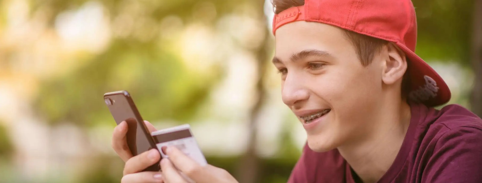 teen boy with a smartphone and a plastic card in his hands
